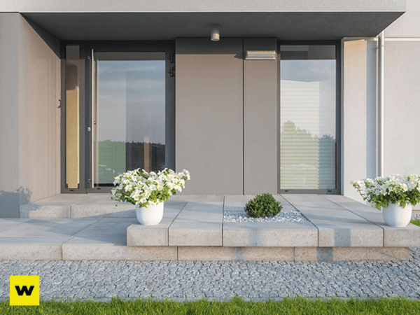 Moderner Hauseingang mit großen Glasflächen, Pflanzkübeln und stilvoller Außenanlage.